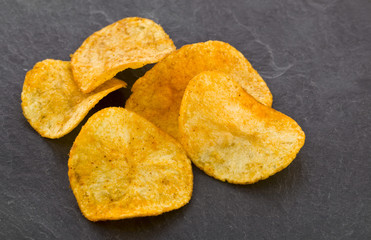 crispy potato chips on a black stone background