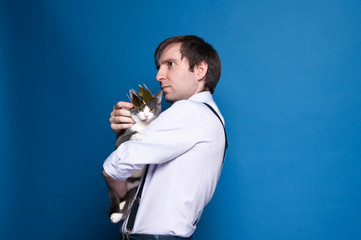 side view of handsome man in shirt and black suspenders looking into distance, holding and stroking...