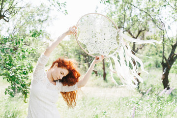 Young red hair woman holding white dream catcher