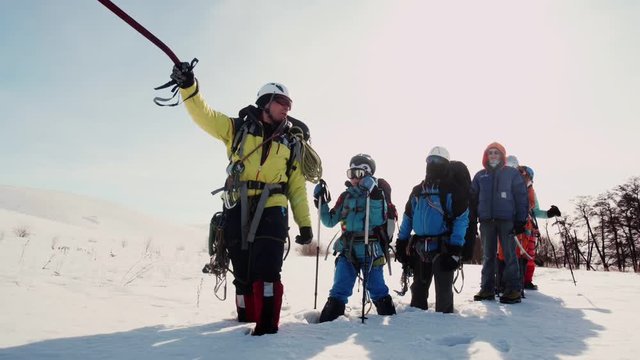 the freight forwarder points the ice ax in the direction of their way. the team stands in the snow and was tired.