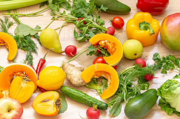 vegetables fruits and greens on wooden background. pear, hot red pepper, pumpkin, persimmon, mango, cucumber, radish, lemon, Apple, dill, parsley, cabbage