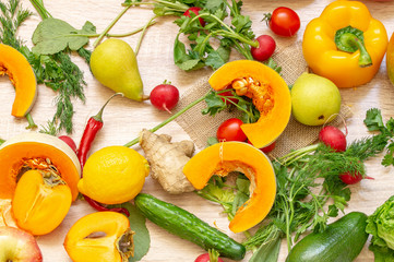 vegetables fruits and greens on wooden background. pear, hot red pepper, pumpkin, persimmon, avocado, cucumber, radish, lemon, Apple, dill, parsley, cabbage