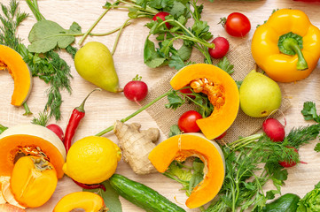 vegetables fruits and greens on wooden background. pear, hot red pepper, pumpkin, persimmon, cucumber, radish, lemon, Apple, dill, parsley, cabbage