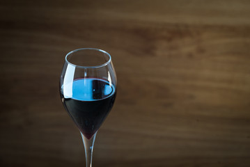 Pouring red wine into the glass against wooden background