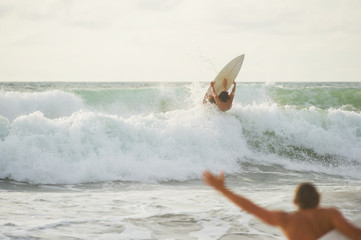 Surfer with a tanned body performs a trick on a short board - a jump over the waves. 