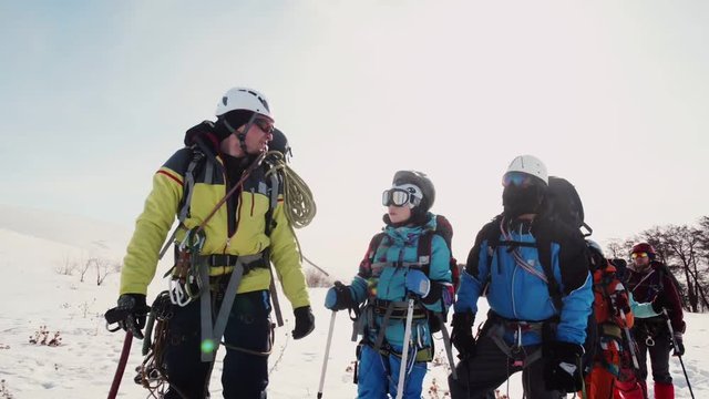 senior of the team of climbers shows the direction of the path hand with an ice pick. the team listens to him attentively.
