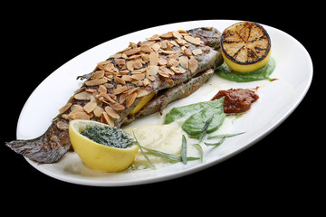 Trout with crispy almond crust and baked mashed potatoes on black background