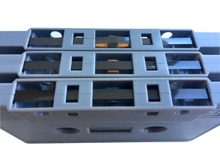 Old classic audio gray tape cassette on film overlay isolated on white background
