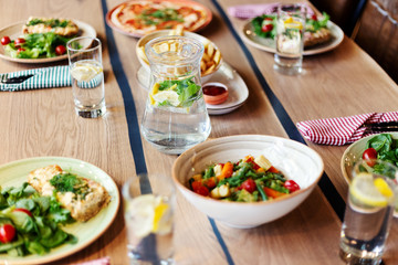 Closeup dishes with meals, pitcher and glasses of drink served on table for four