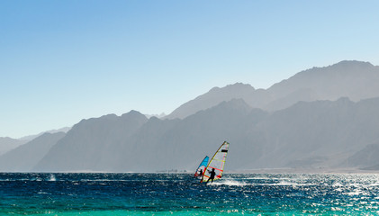 two windsurfers ride on the background of high rocky mountains in Egypt Dahab South Sinai
