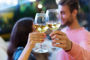 Close-up of young loving couple holding glasses of wine and looking affectionately at each other