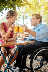 Disabled man in wheelchair and friend drinking beer