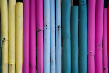 Colorful painted bamboo fence, creative background, decoration, vertical lines. Minimalism concept, vivid colors