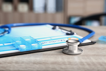 Stethoscope and medical record on table in clinic, closeup