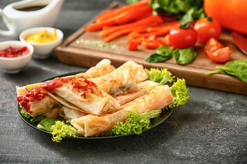 Plate with tasty fried spring rolls on table