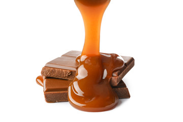 Pouring of liquid caramel onto chocolate on white background
