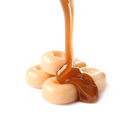 Pouring of liquid caramel onto candies on white background