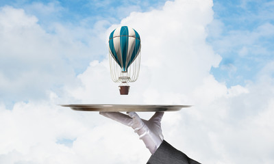 Hand of waiter presenting balloon on tray.