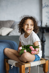 Happy mother's day, daughter gives a bouquet of tulips. African-American girl with a smile without teeth.