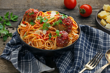 Pasta with meatballs, parmesan and tomato sauce in a clay bowl. Homemade Italian spaghetti on a rustic wooden table.