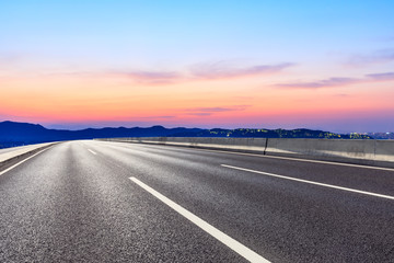 Fototapeta premium Asphalt road and beautiful mountain nature landscape at sunset