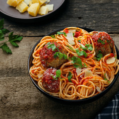 Pasta with meatballs, parmesan and tomato sauce in a clay bowl. Homemade Italian spaghetti on a rustic wooden table. Top view shot.