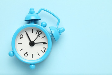 Blue alarm clock isolated on blue background.