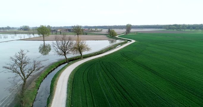 Flooded fields for rice cultivation in the Po Valley, Italy. Panoramic aerial view. Typical countryside landscape of northern Italy with dirt roads, fields and ancient farms.