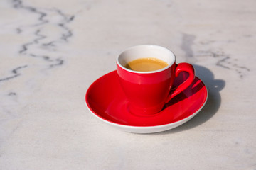 Rote Espressotasse auf weißem Bistrotisch aus Marmor