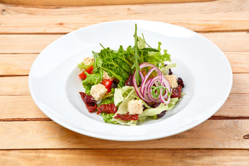 vegetarian salad with dried tomatoes and croutons on the wooden background