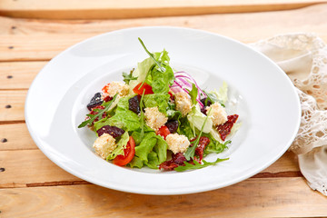 vegetarian salad with dried tomatoes and croutons on the wooden background