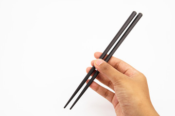 A hand holding a black wooden chopsticks isolated on white background 
