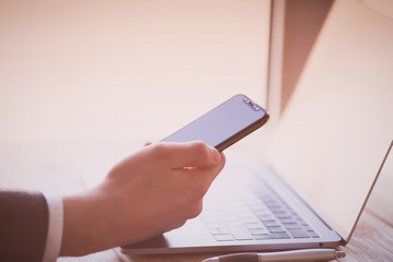 Businessman working with modern devices. Close up male hands, smart phone and laptop. Business, technology, office concept. 