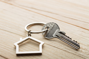 House key with a keychain on wooden desk concept for real estate