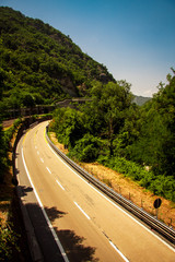 Asphalt road in the mountains with soft sky on the background.
