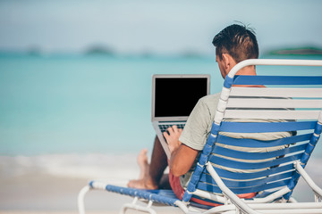 Young man with tablet computer during tropical beach vacation