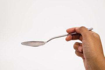 A hand holds a steel spoon isolated on white background