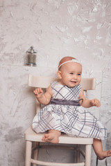 Naklejka premium a little girl in a dress sits on a chair and smiles