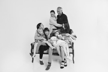 group of people on a white background: adults and children with toys sitting on the same couch