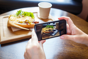 Young woman taking photo of her lunch in cafe
