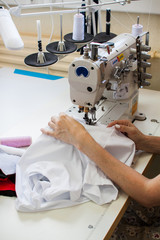 Hands of a girl who sews clothes on a sewing machine. Garment factory