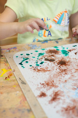 Bright paints, paper, brushes in the children's drawing lesson. Children's drawings, hands