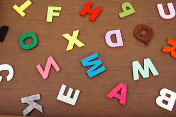 Scattered colorful alphabet letters isolated on wooden texture background. Creative concept.