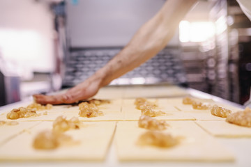 Fototapeta premium Caucasian hardworking baker making rolls with jam. Bakehouse interior.