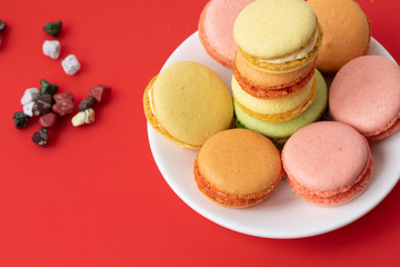 Pile of sweet and colourful french macaroons on red background