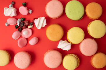 Pile of sweet and colourful french macaroons on red background