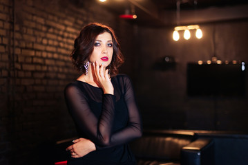 portrait of a beautiful brunette girl in a black dress in a dark room 1