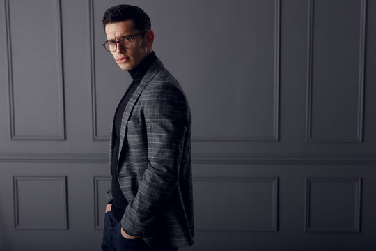 Handsome young brunette model, wearing in grey jacket, looking with attitude, isolated on grey background. Copy space.