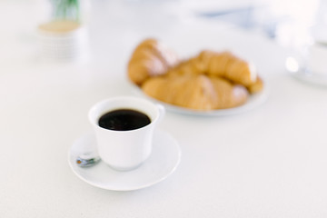 Breakfast with fresh coissants with coffe and milk on white table. Golden croissant.