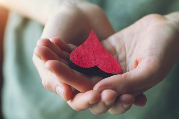 female hand holding red wooden heart, love, care concept, blood donation, world heart day, heart...